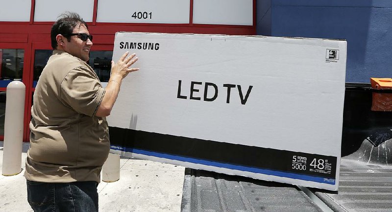 Edward Calixto slides a new television into his pickup in Hialeah, Fla., in May. “Consumer spending looks rock solid,” one economist said this week.