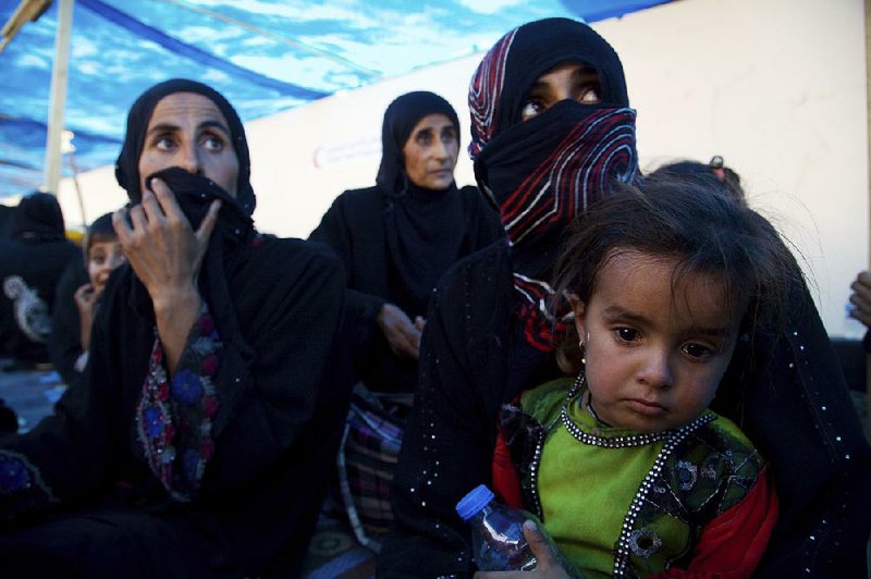 Displaced Iraqi women and children wait last Saturday at an evacuation point on the outskirts of Tal Afar.