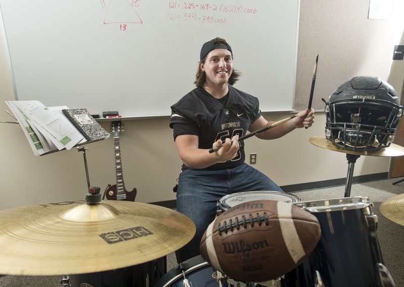 Carson Little, Bentonville senior, poses for a photo Saturday, Aug. 19, 2017, with some of his gear at the Tiger Athletic Complex in Bentonville. Little is Bentonville's starting center, can play a number of musical instruments and takes International Baccalaureate classes. 