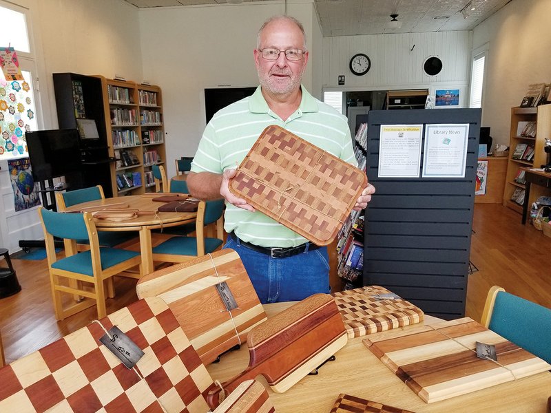 Steve Shock, a retired teacher and coach in the Vilonia School District, stands in the El Paso Community Library with his handmade wooden cutting boards. His work is on display at the library during September as part of the Artist of the Month program.