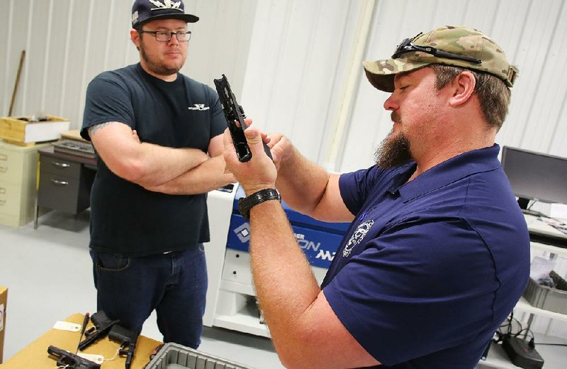 Guy Joubert (right) and Neal Trout inspect a Glock handgun’s polymer frame at Wilson Combat in Berryville. The company now offers custom gunsmith work on Glocks.