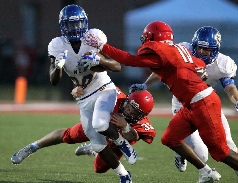 North Little Rock running back Oscar Adaway (26) tries to avoid tackles from Maumelle defenders Harmon Peters (bottom) and Darius Thompson during the second quarter of the Charging Wildcats’ 55-14 victory over the Hornets on Friday in Maumelle. For more high school football photos, visit arkansasonline.com/galleries.