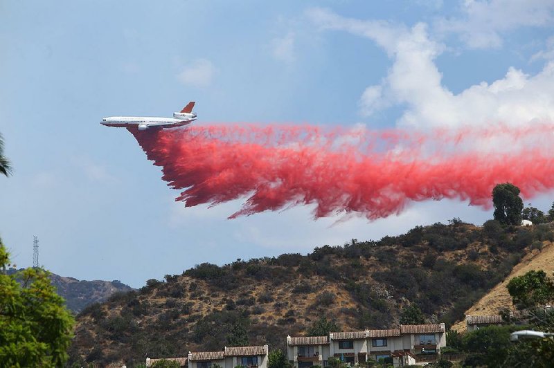 A plane drops fire retardant Saturday on a ridge in Burbank, Calif., as firefighters battle a wildfire.