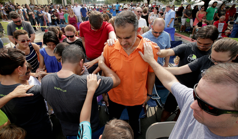 Church members gather to pray around flood victim Carlos Ochoa during Sunday service in the parking lot of the First Baptist Church Sunday, Sept. 3, 2017, in Humble, Texas. The church building was flooded with two feet of water from Hurricane Harvey prompting services to be held in the parking lot. 