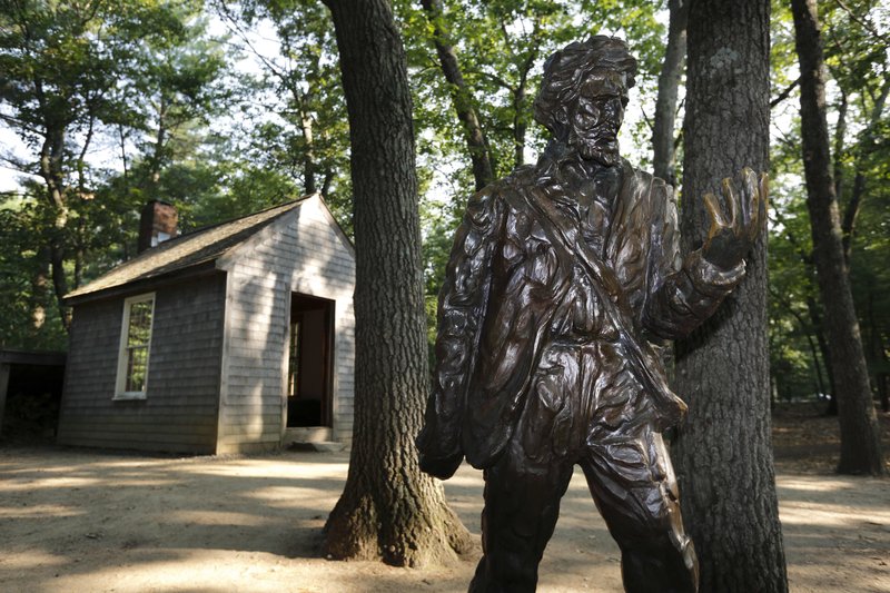 A statue of Henry David Thoreau stands outside a replica of his cabin near the shores of Walden Pond in Concord, Mass.