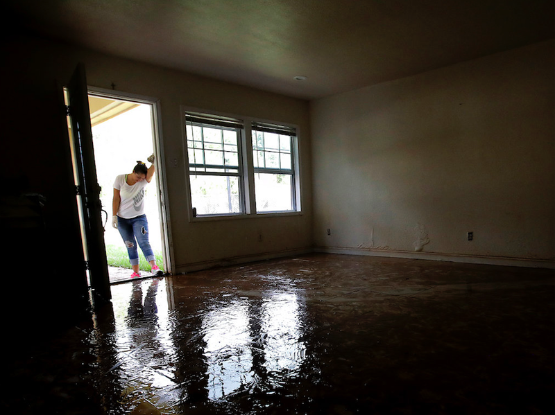 FILE - In this Aug. 31, 2017 file photo, Alejandra Castillo takes a break from carrying water-soaked items out of her family's home after flood waters receded in Houston. Experts say Harvey’s filthy floodwaters pose significant dangers to human safety and the environment that will remain even after levels drop far enough that southeastern Texas residents no longer fear for their lives.