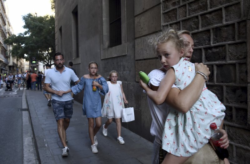 FILE - In this Thursday, Aug. 17, 2017 file photo, people flee the scene in Barcelona, Spain, after a white van jumped the sidewalk in the historic Las Ramblas district, crashing into a summer crowd of residents and tourists. 