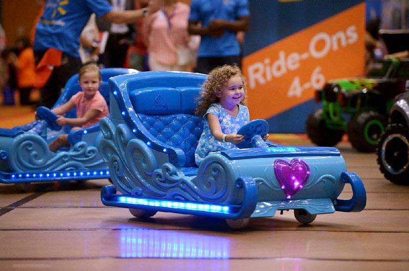 Two children try out motorized Disney Frozen sleighs during Wal-Mart’s Top Rated By Kids event in July in Rogers. 