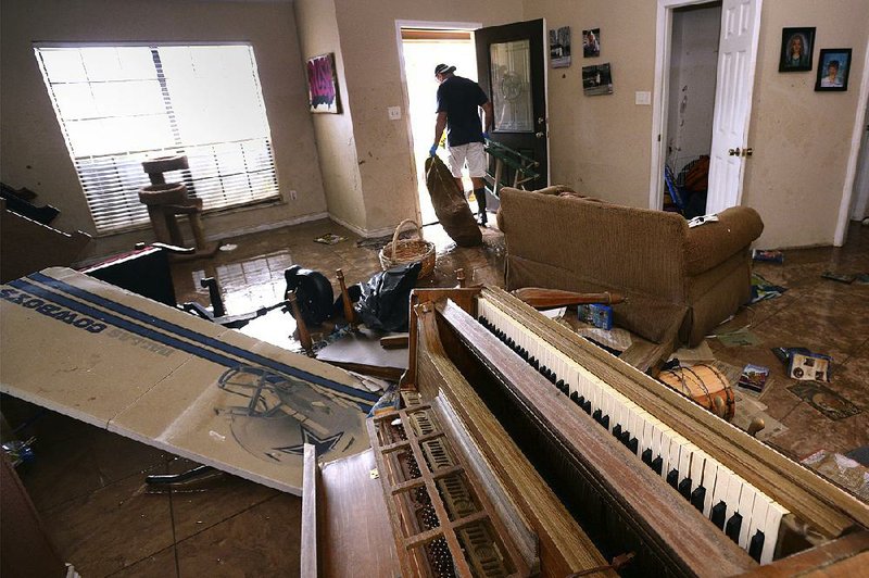 Frankie Hare hauls water-soaked items from his home Tuesday in Beaumont, Texas. 