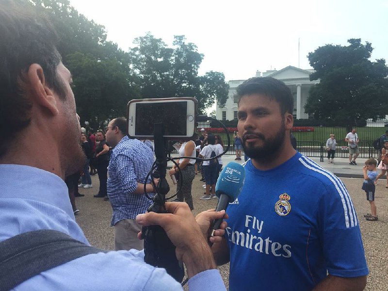 Outside the White House on Tuesday, a French journalist interviews Diego Quinones, 27, of Bentonville, who arrived at age 7 to live in the United States. 