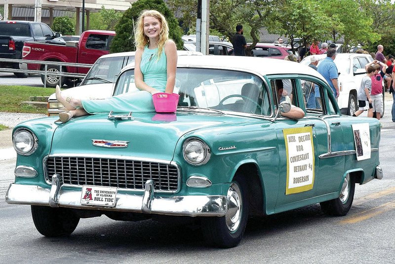 Photo by Mike Eckels Riding on the hood of her father Tim Bottoms&#8217; 1955 Chevrolet Bel-Air, Bethany Roberson throws candy to children lining Main Street for the 2017 Decatur Barbecue Parade on Aug. 5. Bethany was one of six area girls who competed for the title of Miss Decatur Barbecue.