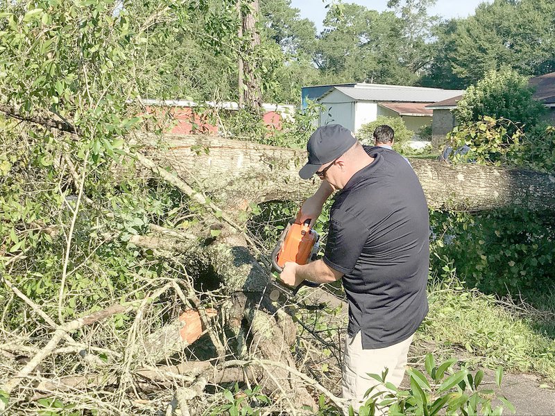 COURTESY PHOTO Chief Chris Workman with Prairie Grove Police Department uses a chainsaw to clear this property from devastation caused by Hurricane Harvey.