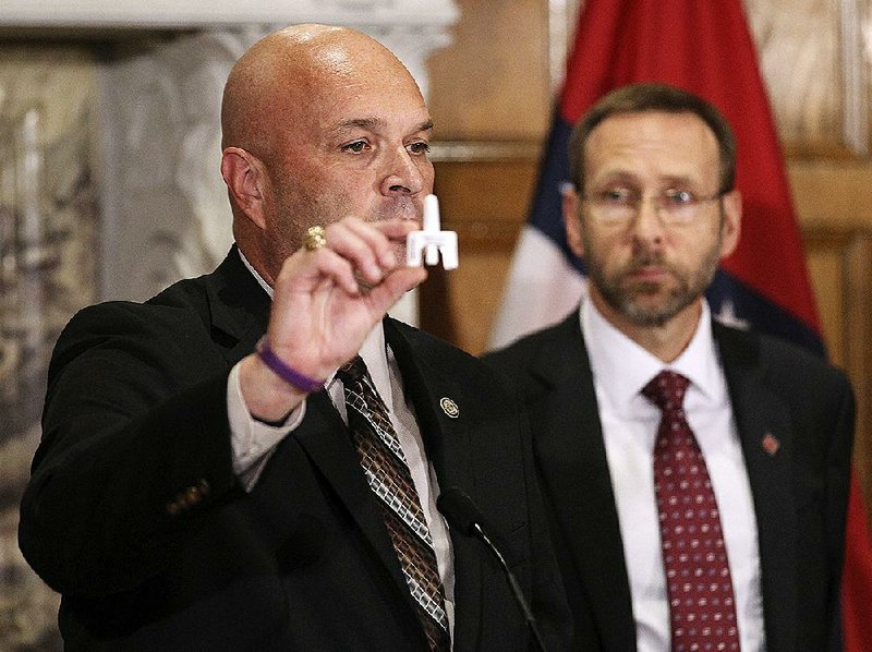 Kirk Lane (left), state drug director, shows the anti-overdose drug naloxone during Wednesday’s announcement at the Capitol. With him is Health Department Director Dr. Nate Smith.