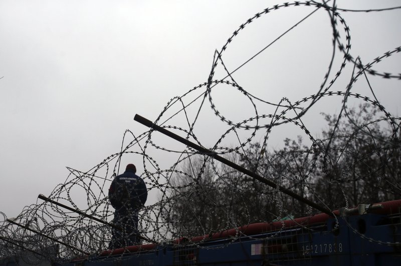 FILE - In this file photo dated Wednesday, Feb. 8, 2017, a Hungarian police officer stands guard at Serbia's border with Hungary near a makeshift camp for migrants in Horgos, Serbia. The European Court of Justice on Wednesday Sept.6, 2017, rejected efforts by Hungary and Slovakia to stay out of a European Union scheme to relocate refugees. (AP Photo/Darko Vojinovic, FILE)