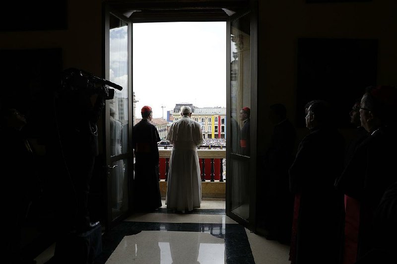 Pope Francis looks out over the crowd Thursday from the balcony of the Cardinal’s Palace to offer a blessing in Bogota. On the first full day of his visit, the pope urged Colombians to “heal wounds, build bridges, strengthen relationships and support one another.”  