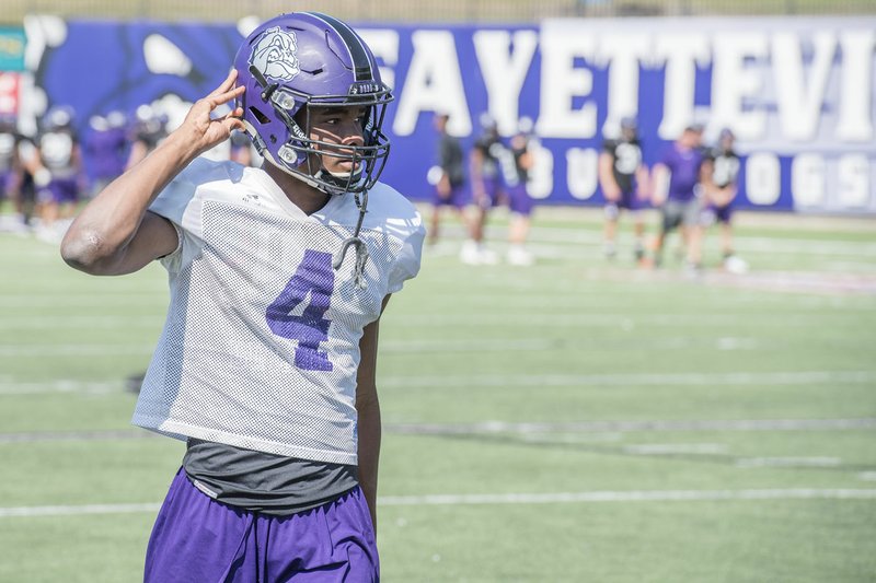 NWA Democrat-Gazette/J.T. WAMPLER Fayetteville’s Kris Mulinga buckles his chinstrap during practice Wednesday at Harmon Field in Fayetteville. The senior receiver has emerged as one of the Purple’Dogs’ top targets because of his big-play ability.