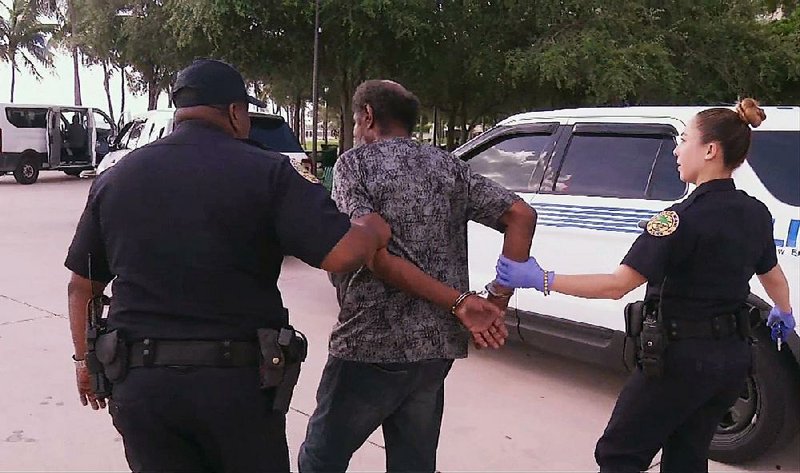 Officials in Miami escort a homeless person to a shelter Friday ahead of Hurricane Irma. 