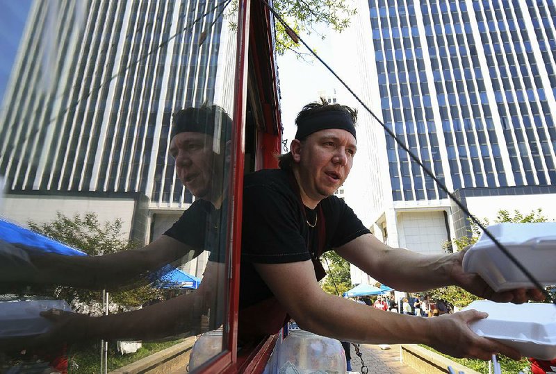 Arkansas Democrat-Gazette/STATON BREIDENTHAL --9/8/17-- Kyler Nordeck (cq), owner of Katmandu Mo Mo, delivers orders to customers Friday during the opening day of Main Street Food Truck Fridays at the corner of Capitol Ave. and Main Streets in Little Rock. Sponsored by the Downtown Little Rock Partnership, food trucks will be at the location every Friday through Oct. 27 from 10:45 a.m until 1:30  p.m. with the exception of Oct. 6. 