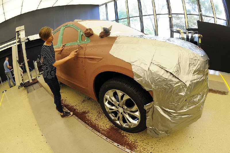 General Motors creative clay sculptor Gianna Ball smooths loose clay on a model of a 2018 Buick Enclave frame late last month at the GM Tech Center in Warren, Mich. 
