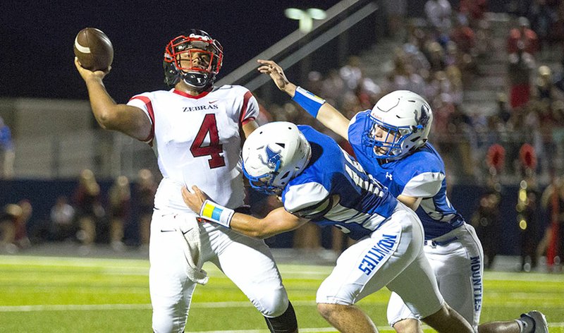 Timothy Howard (center) of Rogers High wraps up Claremore, Okla., quarterback Christian Gotcher as he attempts to pass Friday at Whitey Smith Stadium in Rogers.