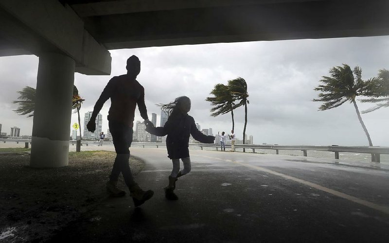 Winds from the outer edges of approaching Hurricane Irma whip the trees and surf Saturday along the Rickenbacker Causeway in Miami.