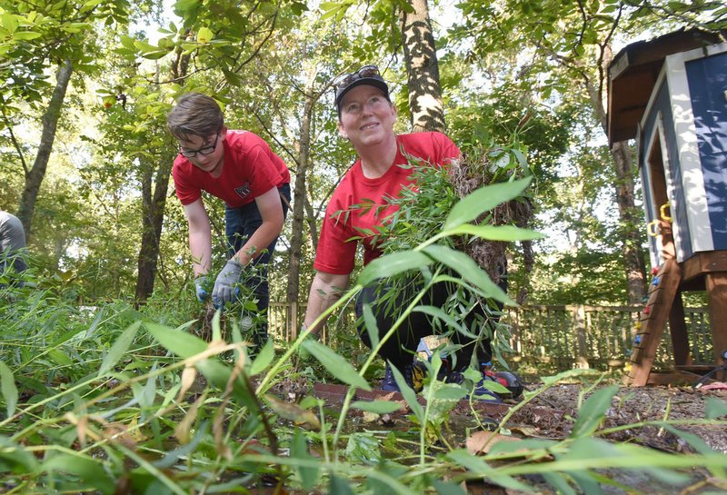 NWA Democrat-Gazette/FLIP PUTTHOFF Nicholas Pleiman, 14, and his mom, Jennifer Pleiman, members of the Young Men’s Service League, clear weeds Saturday at Restoration Village in Little Flock. 