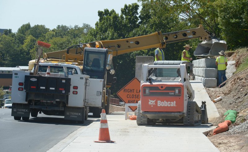 Fayetteville Transportation Division workers assemble a retaining wall Thursday along College Avenue. The city has begun hiring an artist to create a mural on the retaining wall between Cleburn and Prospect streets to be completed by the first of November.