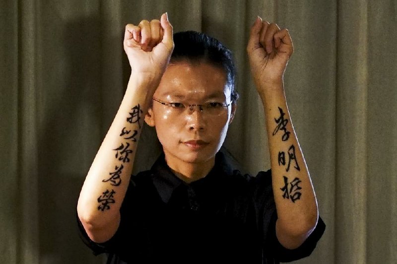 Lee Ching-yu, wife of Taiwanese activist Lee Ming-Che shows the words tattooed on her arms, which read “Lee Ming-Che, I’m proud of you,” to reporters at a hotel after attending her husband’s trial at the Yueyang Intermediate People’s Court in south China’s Hunan province Monday.