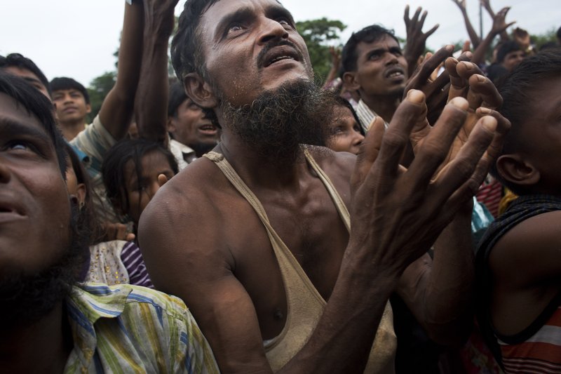 A Rohingya man stretches his arms out for food distributed by local volunteers, with bags of puffed rice stuffed into his vest at Kutupalong, Bangladesh, Saturday, Sept. 9, 2017. 