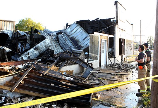 The Sentinel Record/Richard Rasmussen CHARRED REMAINS: Members of the Hot Springs Fire Department look over the remains of a building in the 600 block of West Grand Avenue Monday, after a fire destroyed two buildings and damaged a third.