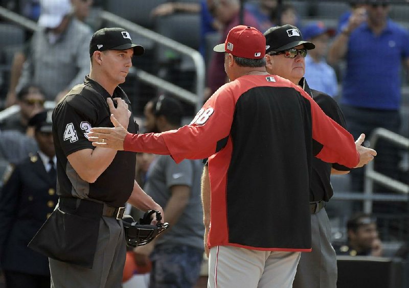 The discussion between Cincinnati Reds Manager Bryan Price (center) and umpires Shane Livensparger (left) and Jerry Layne was just starting to heat up, but then “God Bless America” began. 