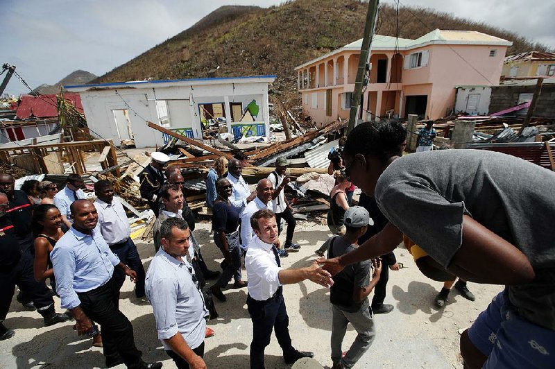 French President Emmanuel Macron (center) greets residents Tuesday during a tour of the storm-ravaged island of St. Martin. He pledged a fast recovery for the island.  