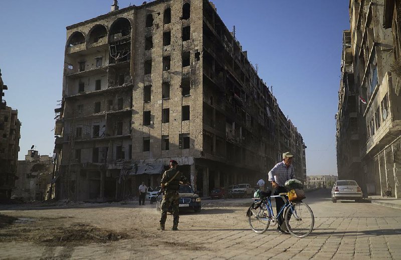 Under the eye of a Syrian soldier, traffic moves Tuesday in what was once a rebel-controlled area of Aleppo, Syria. 