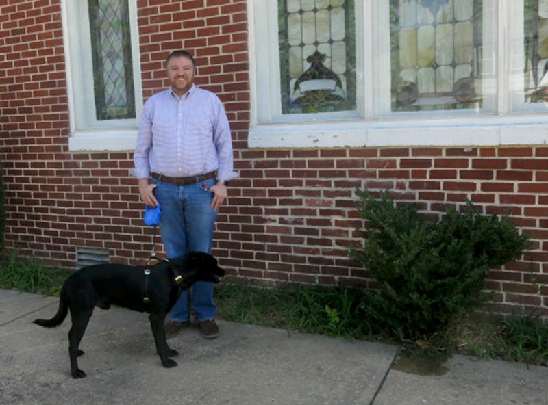 Photo by Susan Holland Heath Williams is the new pastor at the Gravette and Decatur United Methodist churches. He is pictured here outside the Gravette church with his black lab, Shadow, a rescue dog who often accompanies him to the church offices. Williams maintains office hours from 9 a.m. to 4:30 p.m. on Mondays and Wednesdays in Decatur and on Tuesdays and Thursdays in Gravette. He invites all in the area to come by and get acquainted.