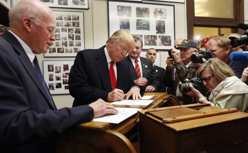 FILE - In this Nov. 4, 2015, photo, New Hampshire Secretary of State Bill Gardner watches, left, as Republican presidential candidate Donald Trump fills out his papers to be on the nation's earliest presidential primary ballot at The Secretary of State's office in Concord, N.H. (AP Photo/Jim Cole, File)