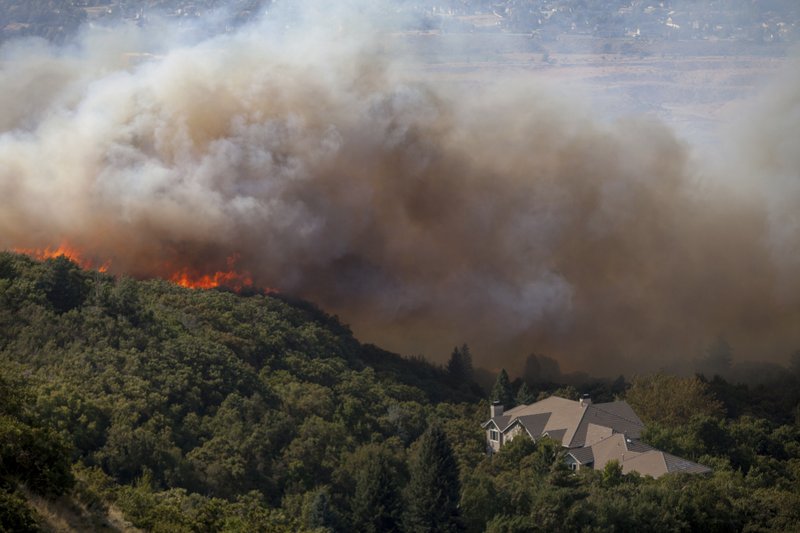 FILE- In this Sept. 5, 2017, file photo, a wildfire burns through residential areas near the mouth of Weber Canyon near Ogden, Utah. Interior Secretary Ryan Zinke is directing all land managers and park superintendents to be more aggressive in cutting down small trees and underbrush to prevent wildfires.  (Benjamin Zack/Standard-Examiner via AP, File)