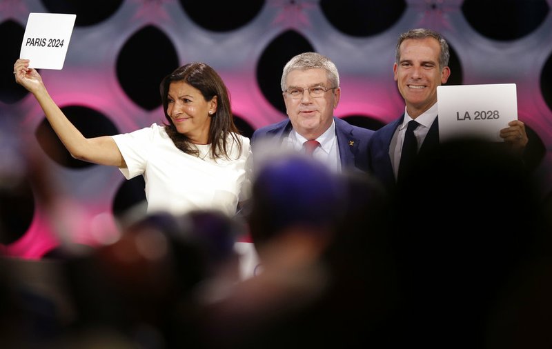 International Olympic Committee President Thomas Bach stands between Paris Mayor Anne Hidalgo, left, and Los Angeles Mayor Eric Garrett at the end of the IOC session in Lima, Peru, on Wednesday, Sept. 13, 2017. 