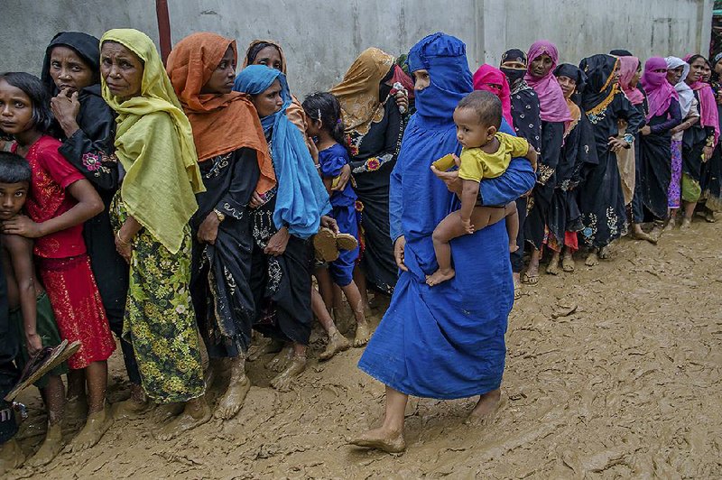 Rohingya women wait their turn Wednesday to collect building material for shelters distributed by aid agencies in the Kutupalong refugee camp in Bangladesh. 