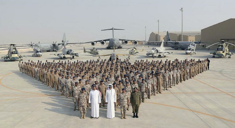 Qatari Emir Sheikh Tamim bin Hamad Al Thani (center front) poses for a photo Monday with the Emiri Air Force at al-Udeid Air Base in Doha, Qatar. Sheikh Tamim bin Hamad Al Thani’s visit to the air base throws into sharp relief the delicate balancing act the U.S. faces in addressing the Qatar crisis. 