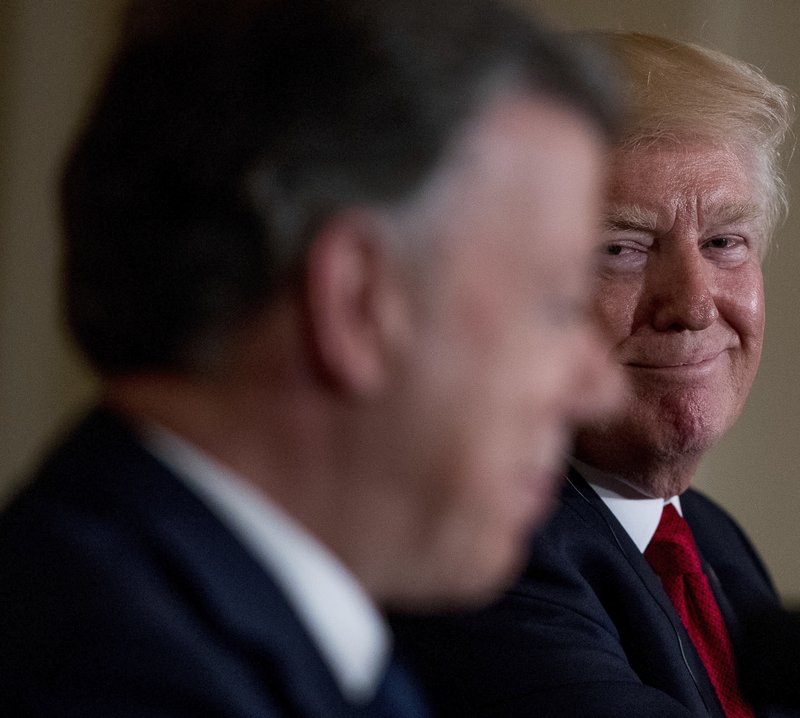 FILE - In this May 18, 2017 file photo, President Donald Trump smiles as he listens to Colombian President Juan Manuel Santos speak during a news conference in the East Room of the White House, in Washington. President Trump is threatening that he may decertify Colombia as a partner in the drug war unless it reverses a record surge in cocaine production in the South American nation. The shock rebuke for Washington's staunchest ally in Latin America came Wednesday, Sept 13, in the White House's annual designation of nations it deems major drug producing or transit zones.(AP Photo/Andrew Harnik, File)