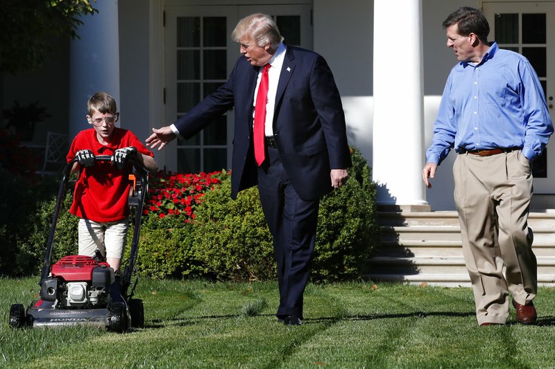 Frank Giaccio, 11, of Falls Church, Va., left, is accompanied by President Donald Trump as he mows the lawn of the Rose Garden on Friday, Sept. 15, 2017, at the White House in Washington, with his father, Greg Giaccio. 