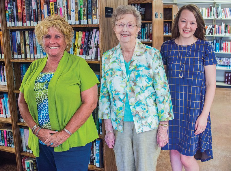 Cave City Library board member Jill Pettersen, from left, librarian Vera Anderson and Friends of the Library member Jessica Anderson stand inside the Cave City Library. The new library opened in May in the former Bank of Cave City building, and the library’s grand reopening took place Aug. 22.