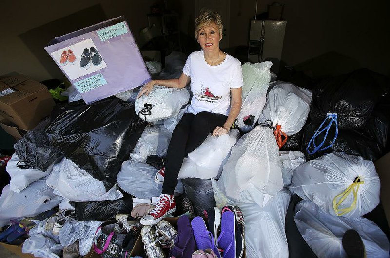 Karla Allen, who with her husband and son founded Ozark Water Projects, sits atop a pile of donated shoes in her garage. The shoes will be sold by the pound to exporters and distributed throughout the world, while proceeds from the shoes will fund the drilling of wells and other clean-water sources in Haiti.