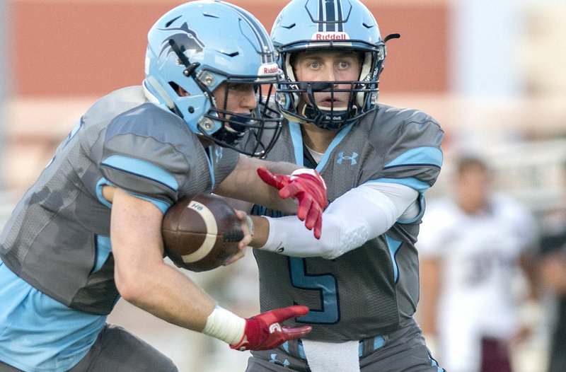 Springdale Har-Ber quarterback Grant Allen (5) hands the ball off to running back Payton Copher (6) on Friday against Jenks, Okla., at Wildcat Stadium in Springdale.