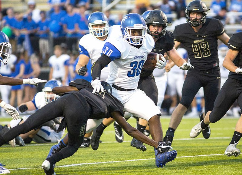 Special to NWA Democrat-Gazette/DAVID BEACH Conway's Michael George (30) attempts to shake off Bentonville High's Dwight Crawford (4) on Friday at Tiger Stadium in Bentonville.