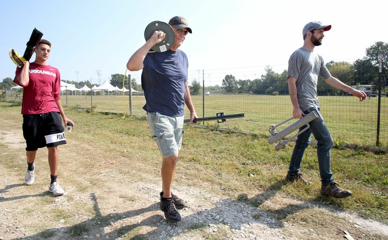 Jason May (from left), a volunteer, Wayne Tuck and Taylor Shelton, director of government affairs and sustainability with the Fayetteville Chamber of Commerce, carry fencing Friday for a parking perimeter at Mae Farm in Fayetteville for the annual NWA Hispanic Heritage Festival presented by the chamber. The first day of the festival begins today at Mae Farm at Lake Fayetteville. The second day of the festival — Sunday — is downtown on the square in Fayetteville. The festival provides an opportunity to access the arts, culture and recreation of Hispanic and Latino Arkansans and Americans.