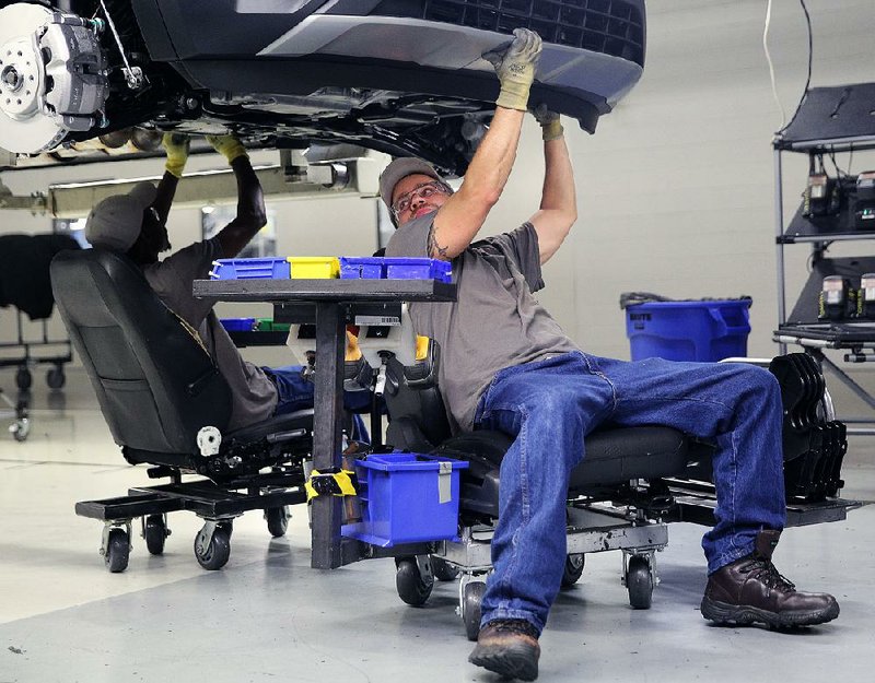 Employees at Volkswagen’s assembly plant in Chattanooga, Tenn., work on a car Thursday. Industrial output fell last month, the Federal Reserve said Friday. 