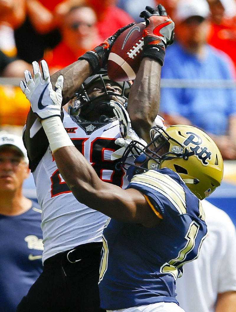 Oklahoma State wide receiver James Washington (28) makes a catch over Pittsburgh defensive back Avonte Maddox during the No. 9 Cowboys’ 59-21 victory over the Panthers on Saturday in Pittsburgh. Washington finished with five catches for 124 yards.