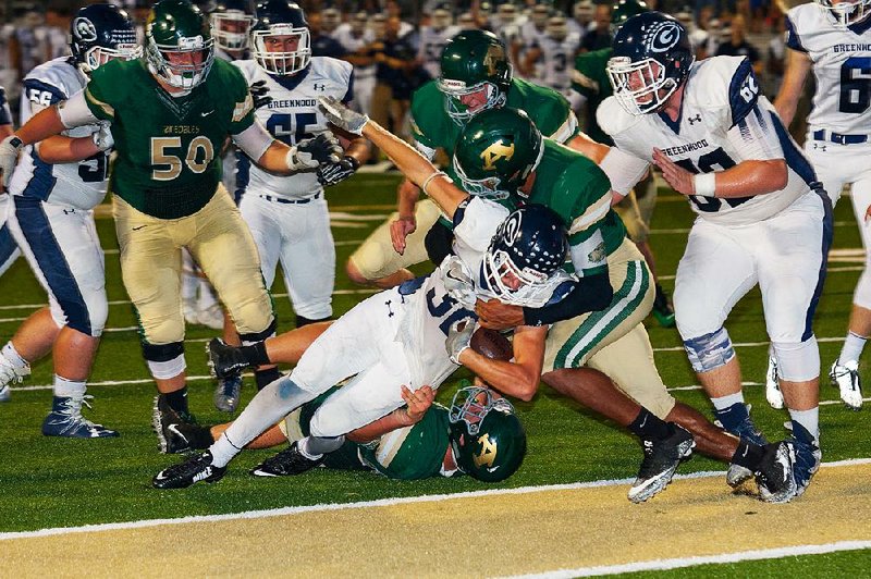 Kenny Wood of Greenwood (middle) fights off two Alma defenders Friday to score a touchdown during the Bulldogs’ 54-28 victory over the Airedales in Alma. For more high school football photos, visit arkansasonline.com/galleries.