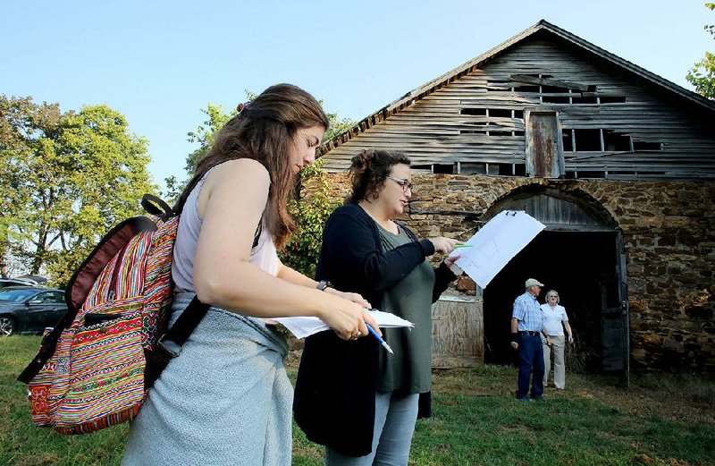 Lauren Lambert and Katie Murphy, graduate students at the University of Louisiana at Lafayette, review architectural documents Friday in front of the horse barn at Fitzgerald Station in Springdale. Students from the university will come up with plans for the site, which once was a stagecoach stop on the Butterfield Overland Express mail route. dav got
